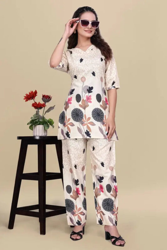 Woman wearing a floral outfit with sunglasses, standing next to a small table with a plant on a beige background
