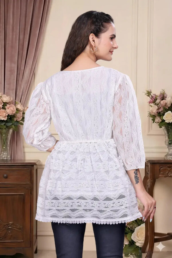 Woman wearing a white lace top in an elegant room setting.