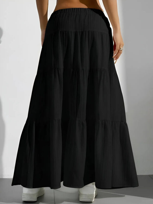 Black tiered skirt worn by a person on a plain background