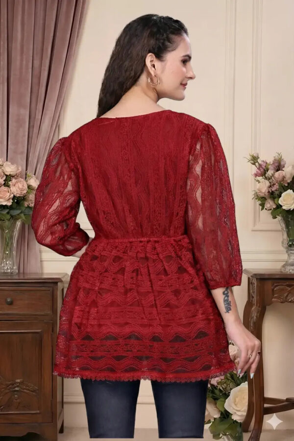 Woman wearing a red lace dress in an elegant room with floral arrangements.