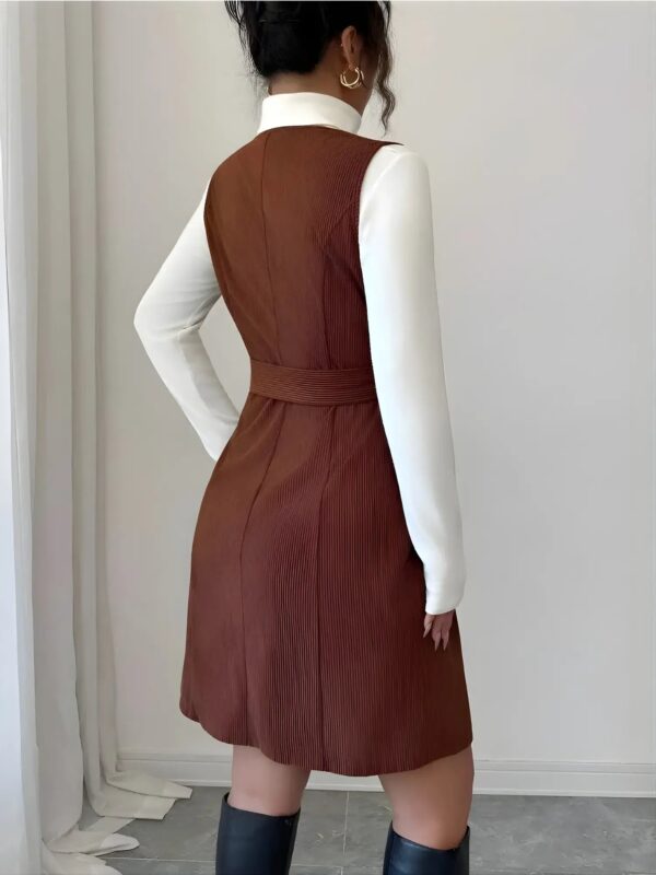 Person wearing a brown dress over a white shirt against a neutral background